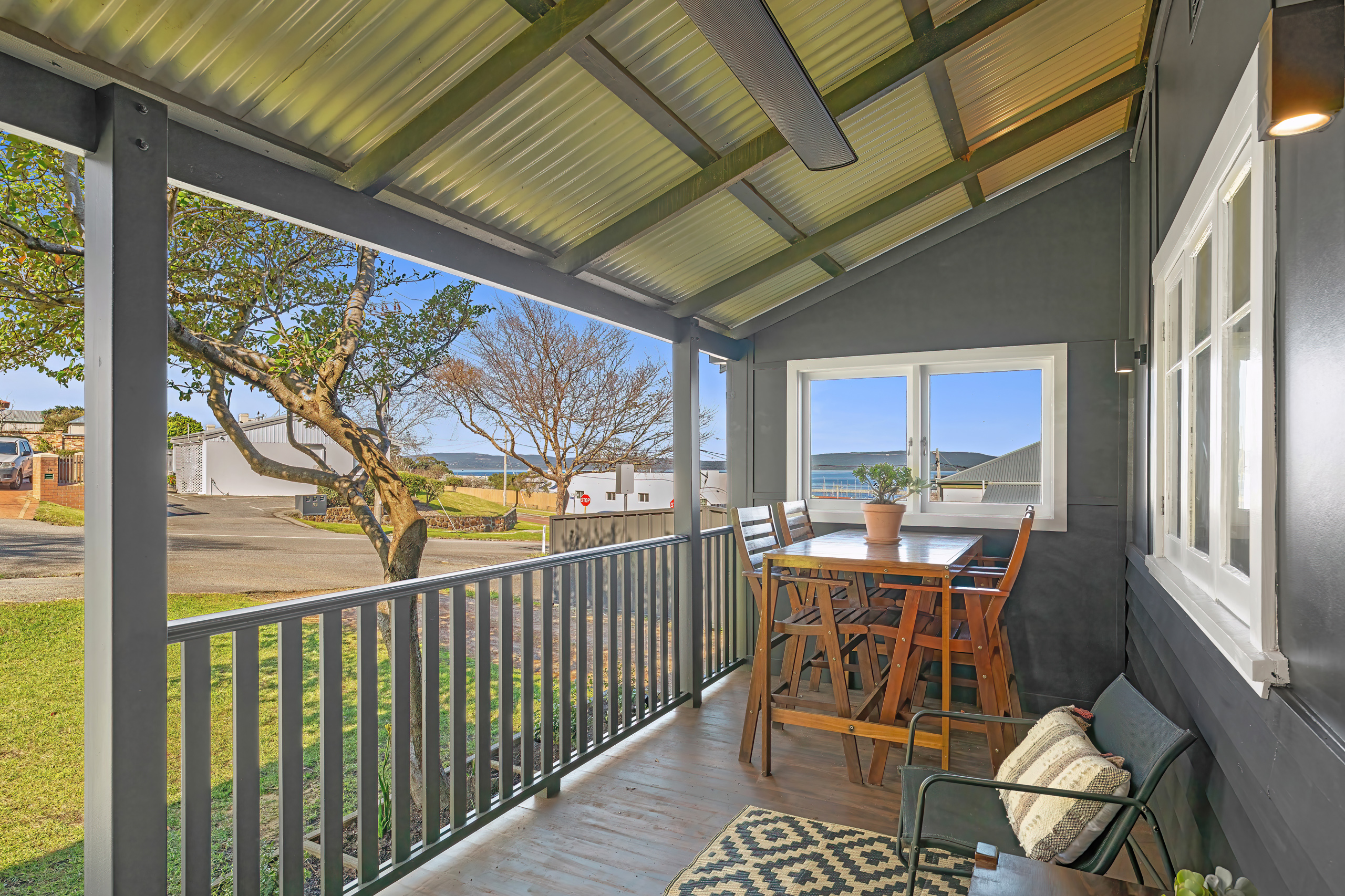 Covered front porch from far end with harbour glimpse, outdoor dining and overhead heater