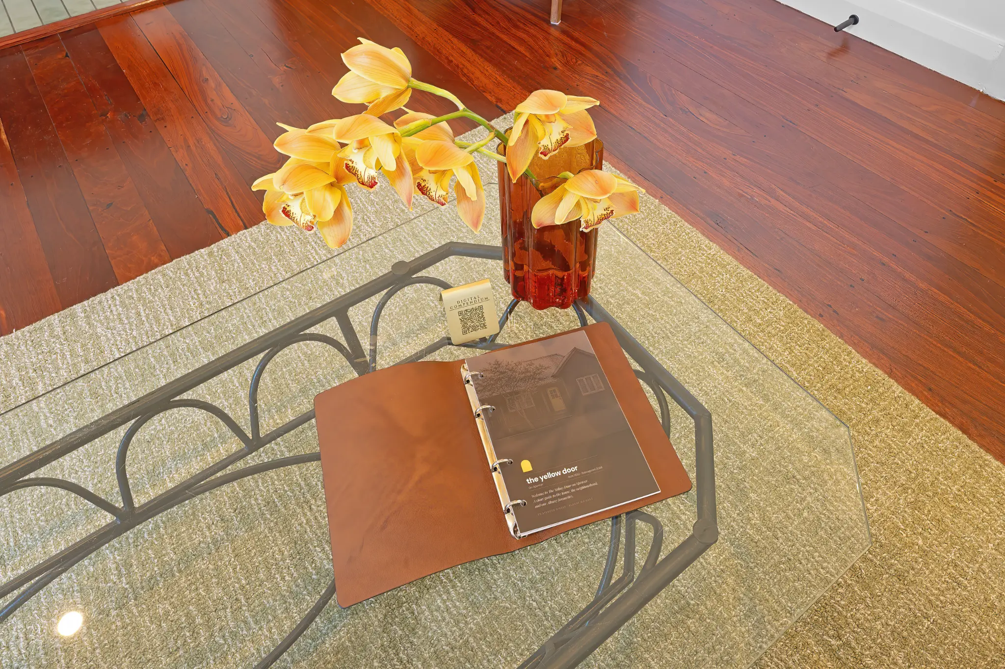Branded Yellow Door guest compendium and orange orchids on glass coffee table with jarrah floors