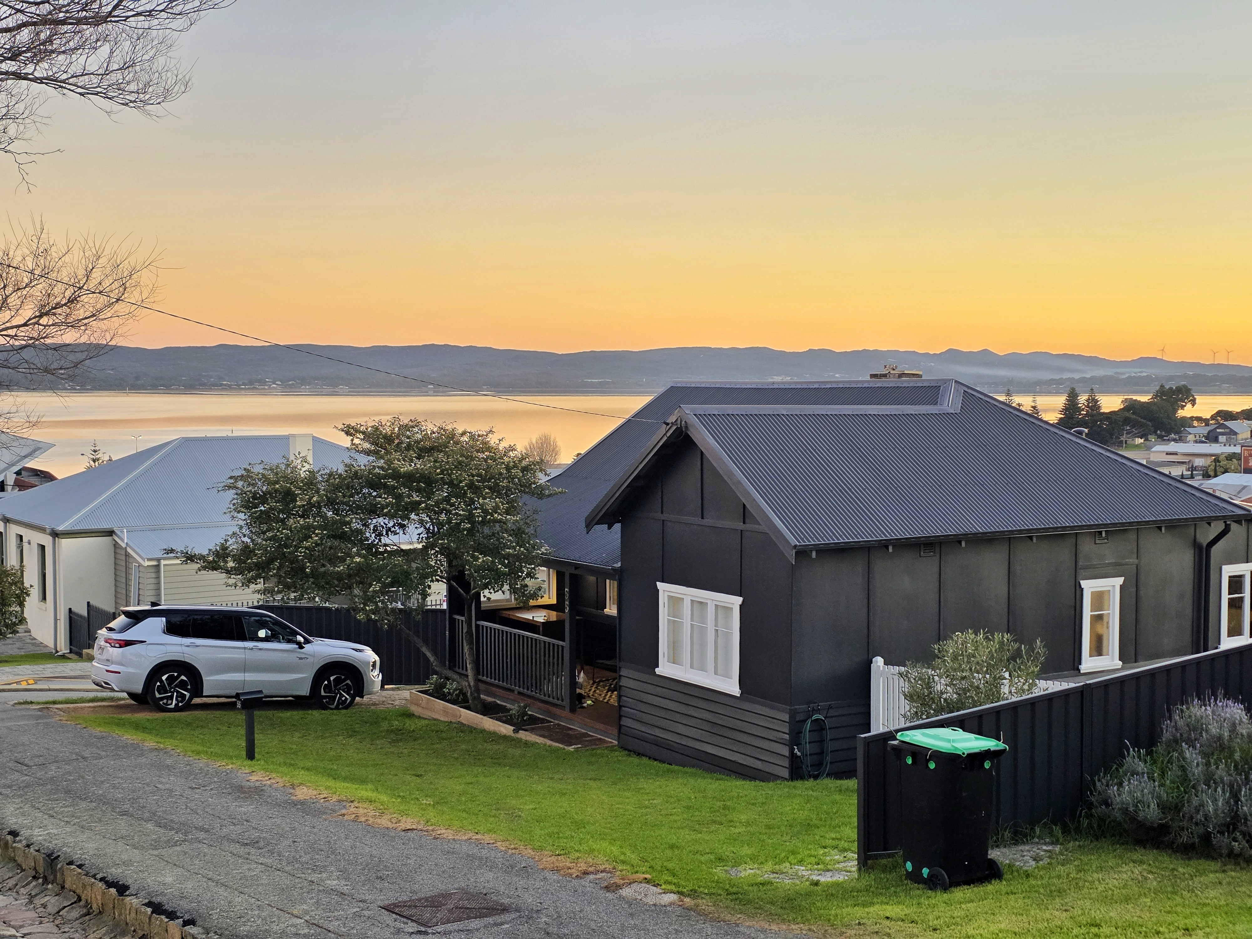 The Yellow Door on Spencer cottage at golden sunset with full Princess Royal Harbour panorama behind it