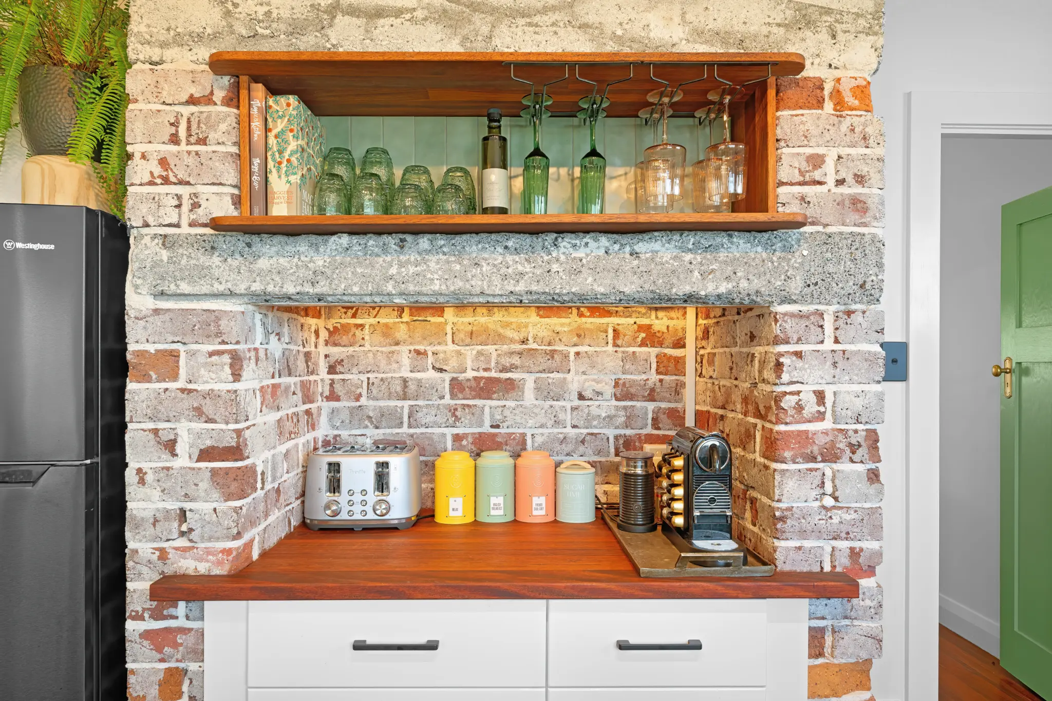 Coffee station with Nespresso machine, toaster and colourful canisters set into exposed brick chimney alcove