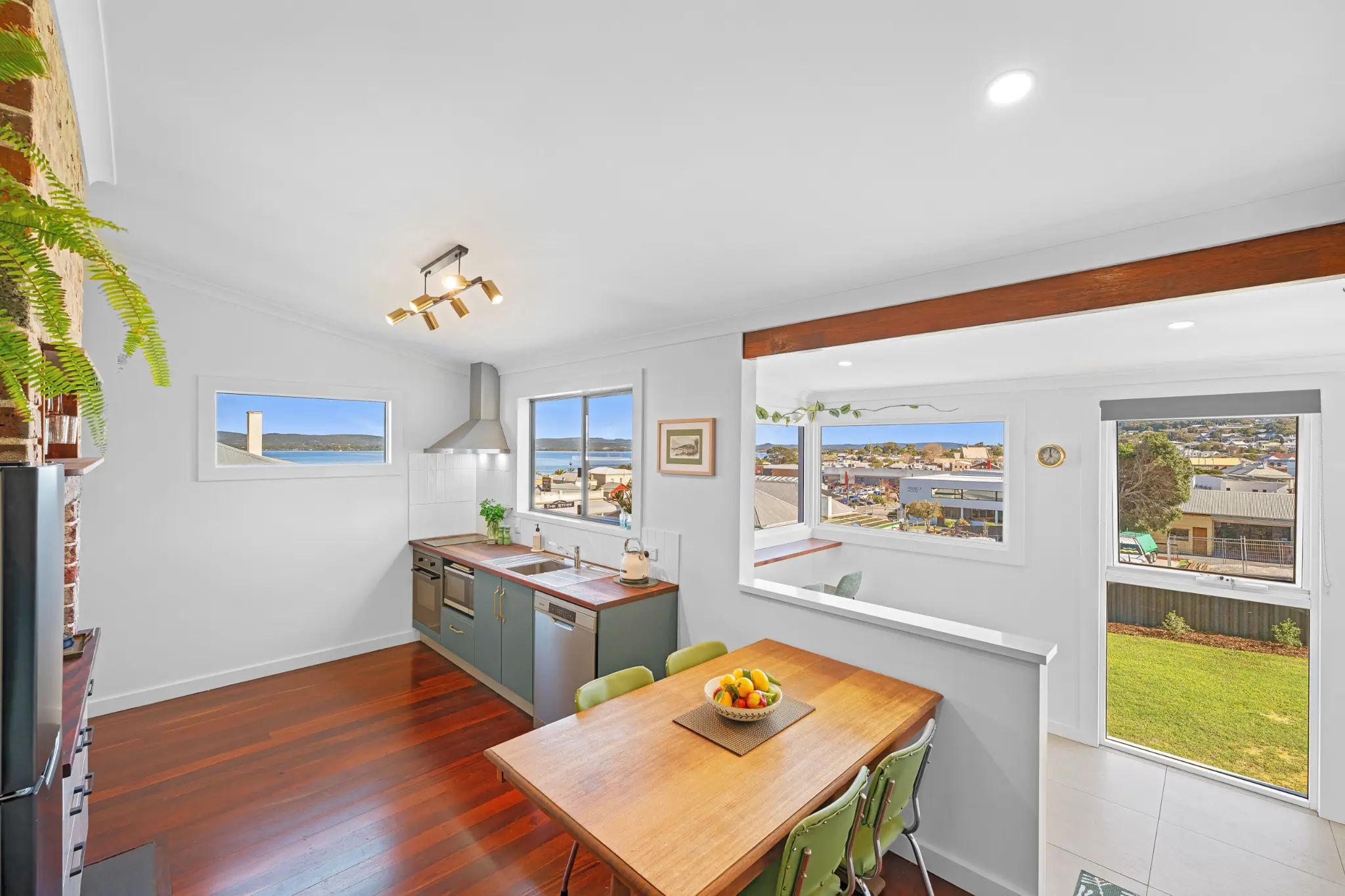 Kitchen and dining area with harbour views through three windows and backyard visible