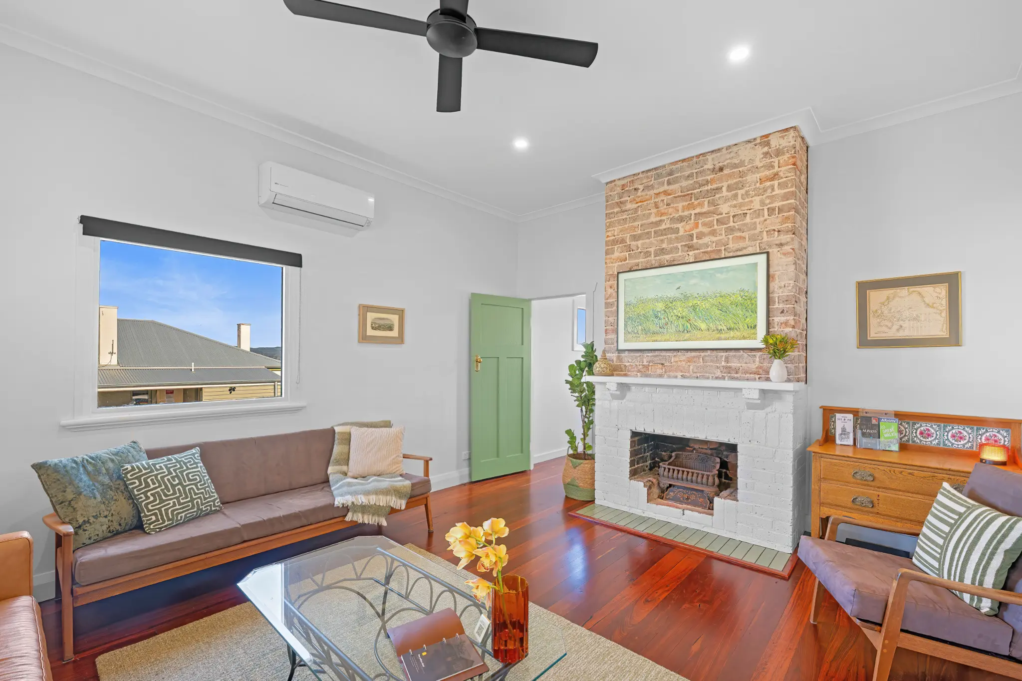 Living room with exposed-brick decorative fireplace, timber-framed daybed and polished jarrah floors
