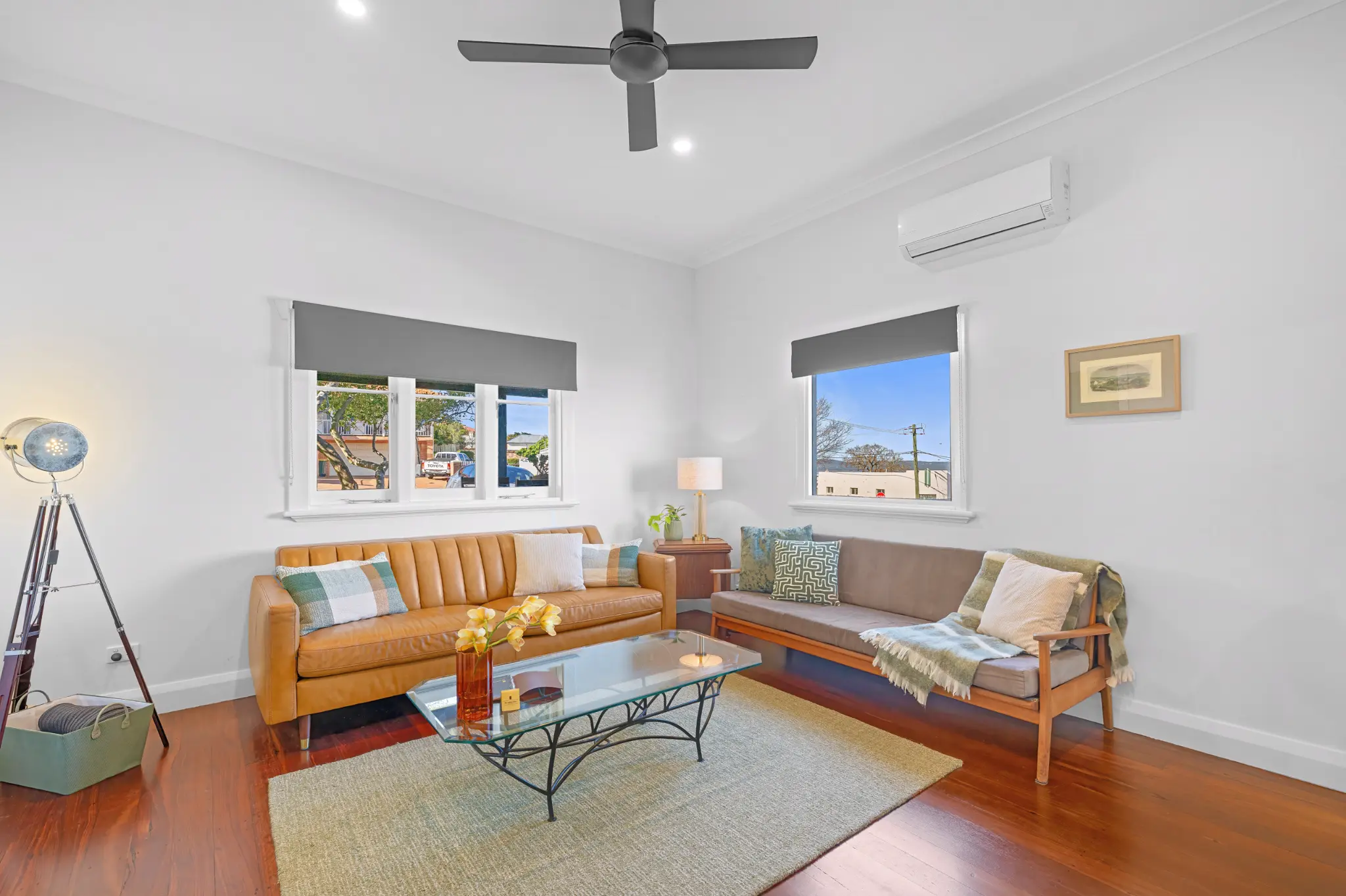 Bright living room with two sofas, split-system AC and two windows with blue sky